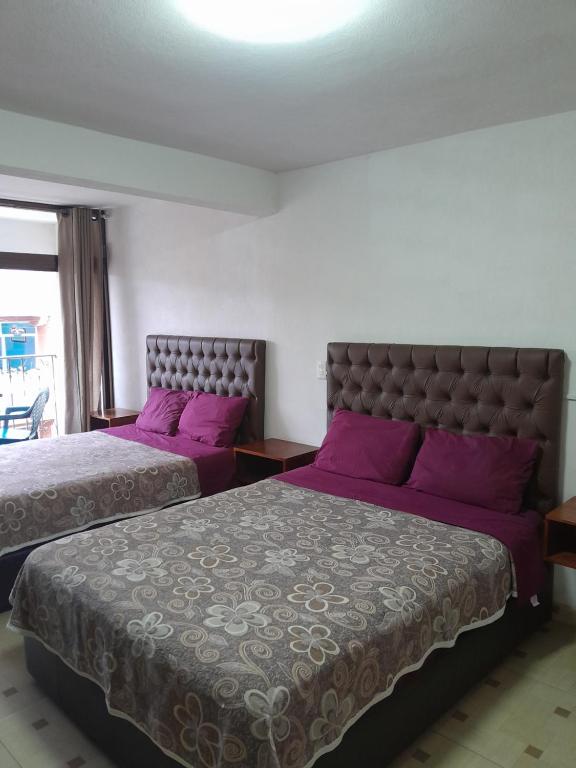 2 camas con almohadas moradas en un dormitorio en Hotel Posada Doña Maria Esther, en Zacatlán