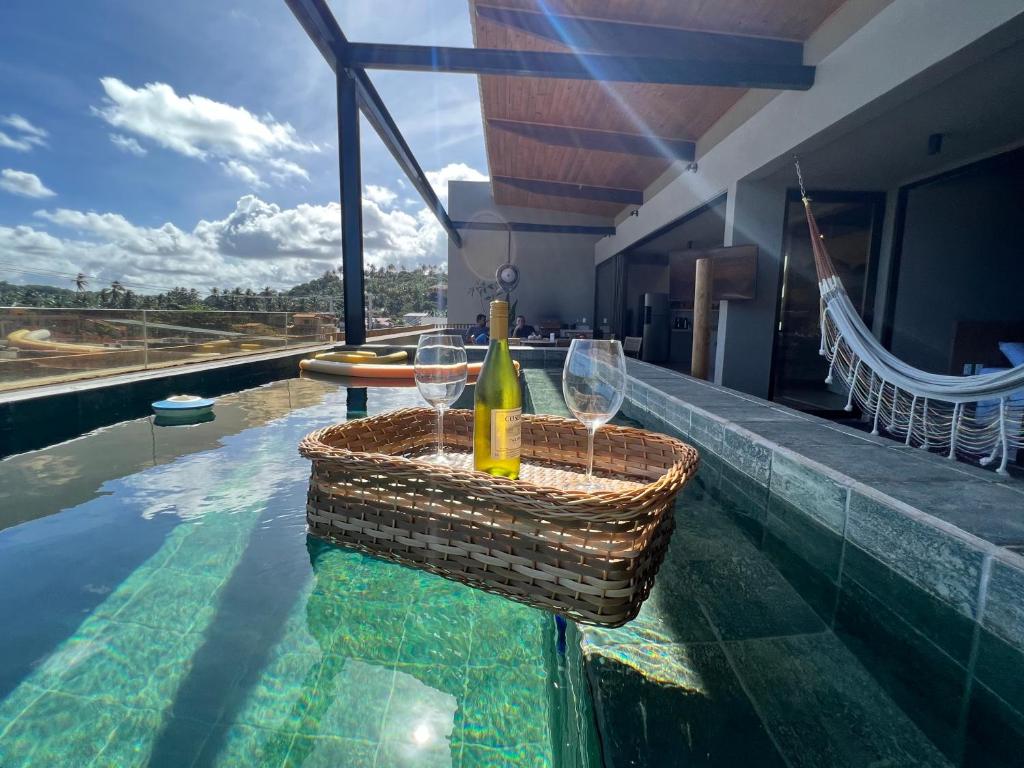 una bottiglia di vino e due bicchieri in piscina di Kanui Mar (cobertura garden) a São Miguel dos Milagres