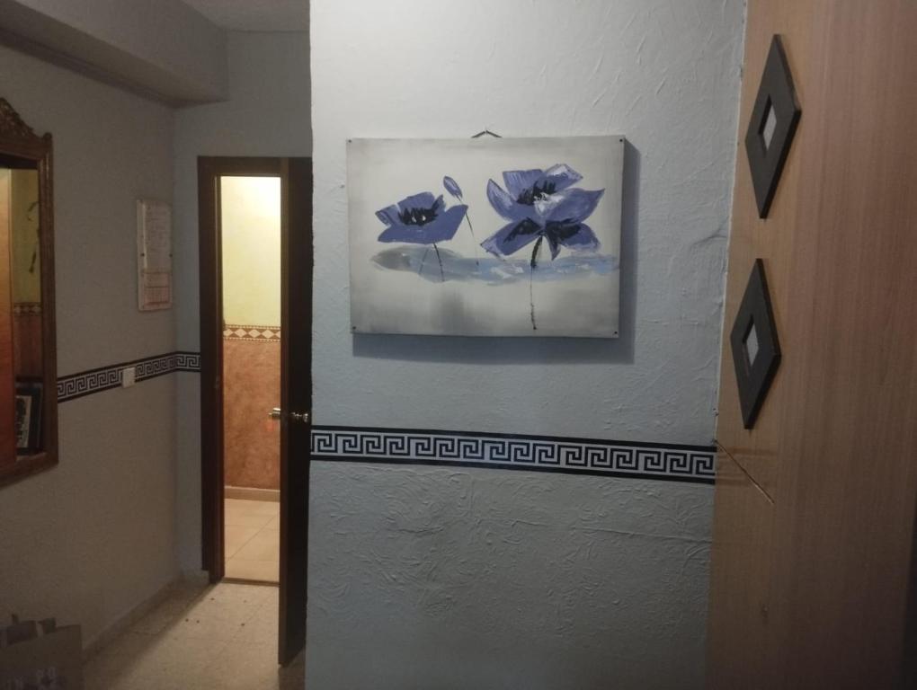 a hallway with a painting of blue flowers on a wall at Hospedería Lucano in Córdoba