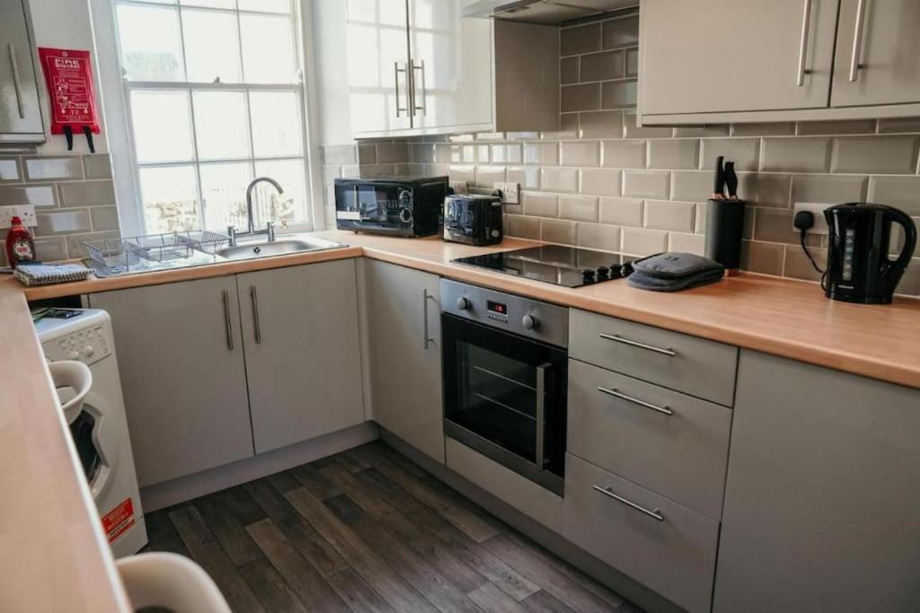 a kitchen with white appliances and a wooden counter top at The Georgian Townhouse - 4 Bed House in Whitehaven