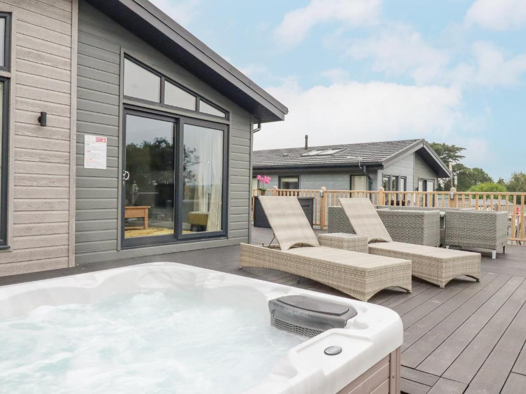a hot tub on the deck of a house at Mordros Lodge in Redruth
