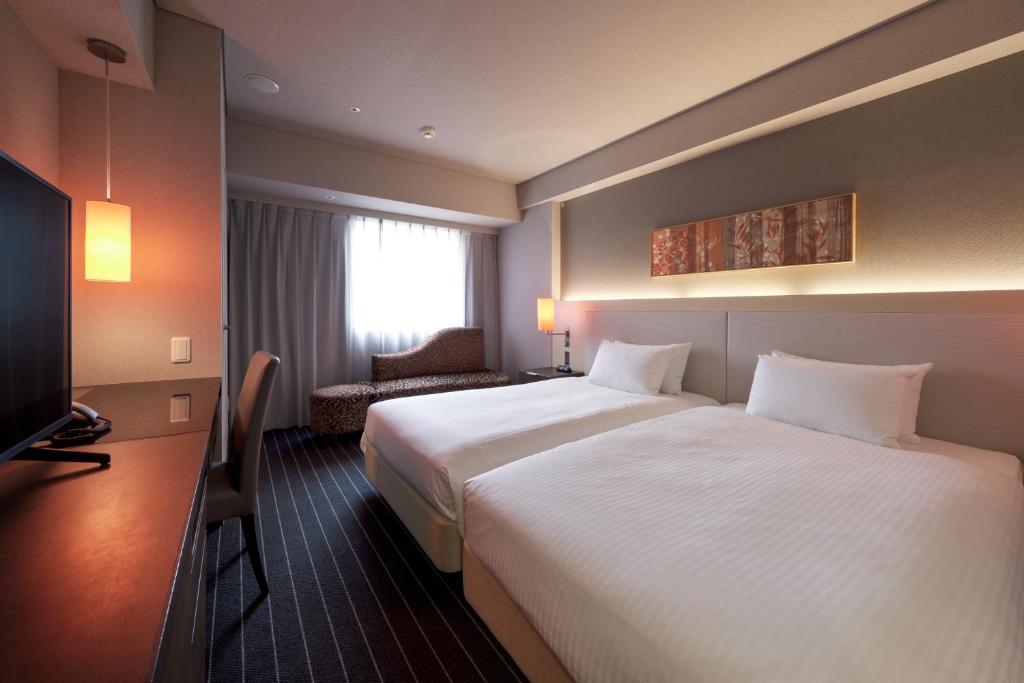a hotel room with a large bed and a television at Hotel Forza Oita in Oita