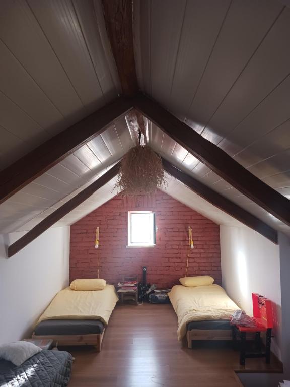 a attic room with two beds and a window at Casa dos pássaros in Carril