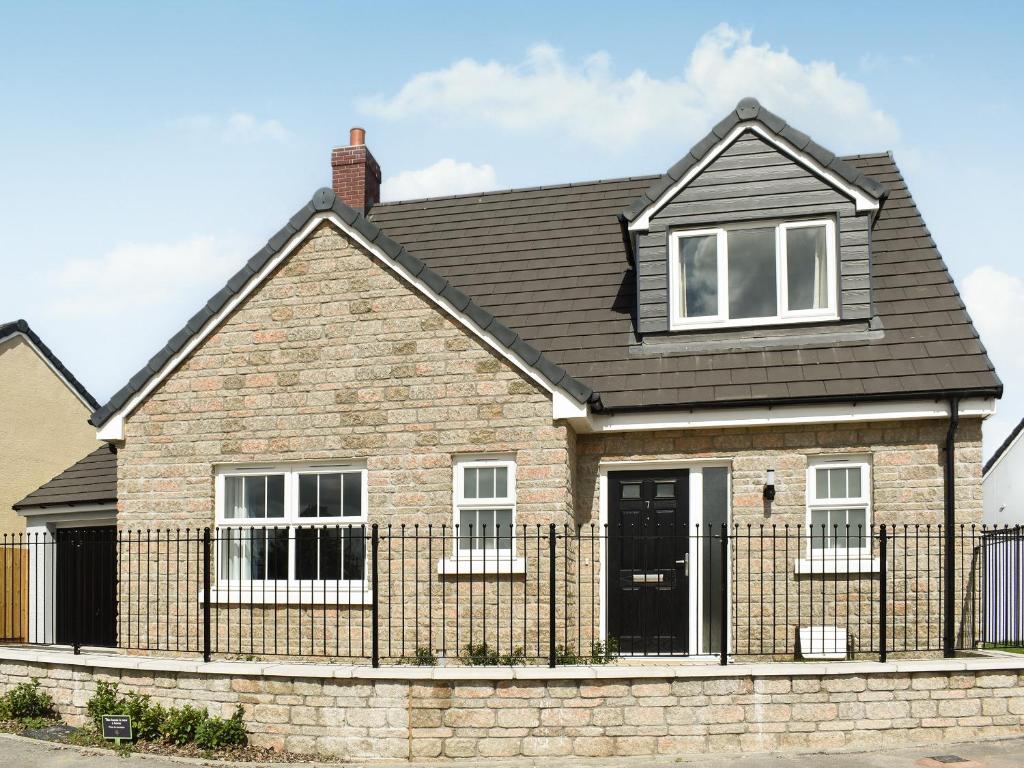 a brick house with a black fence at Magnolia Cottage in Appledore