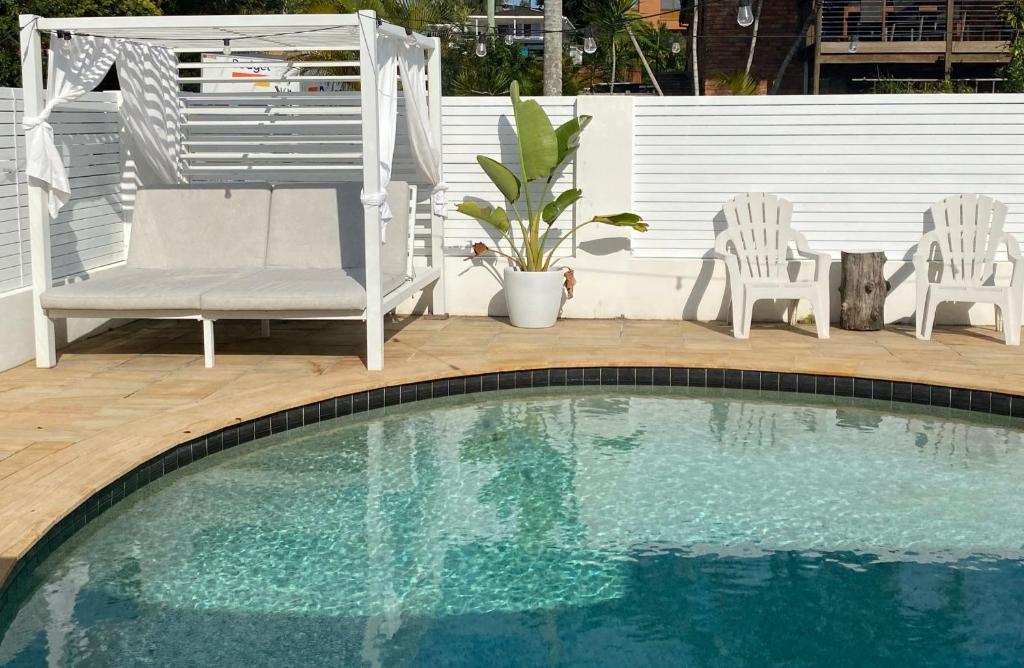 - une piscine avec 2 chaises, une table et une chaise dans l'établissement 600m to Beach, Family Entertainer, Aircon, Pool & Pizza oven, à Maroochydore