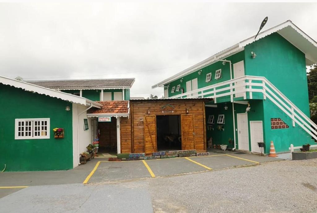 un edificio verde y blanco con aparcamiento en Pousada Don Raton, en Campos do Jordão
