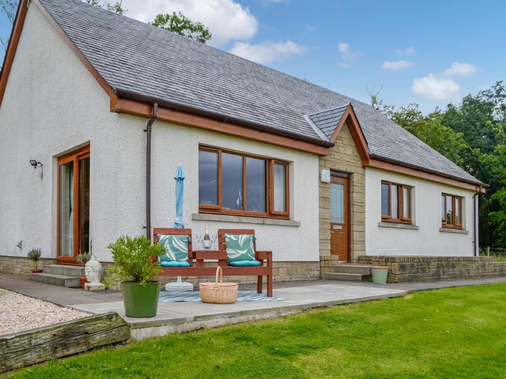 een klein wit huis met een bank in een tuin bij Trelaw in Ochiltree