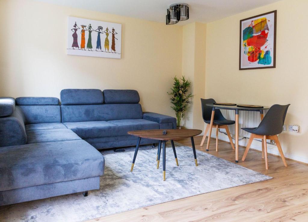 Thamesmead的住宿－Stylish 3 Bedroom and free parking，客厅配有蓝色的沙发和桌子