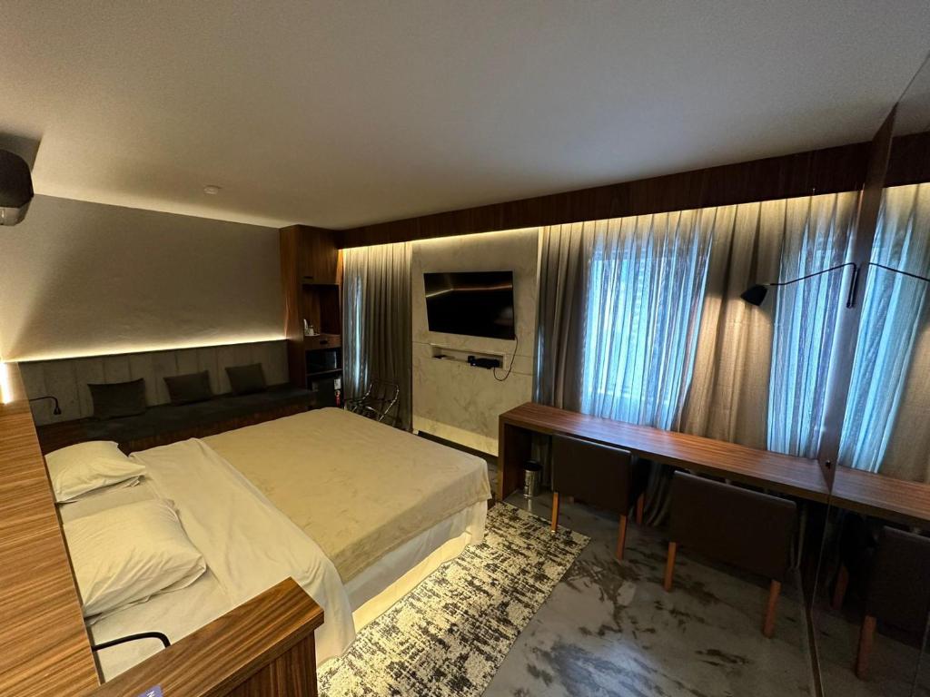 1 dormitorio con cama, escritorio y cortinas en Flat reformado em Hotel nos Jardins! Maravilhoso!, en São Paulo