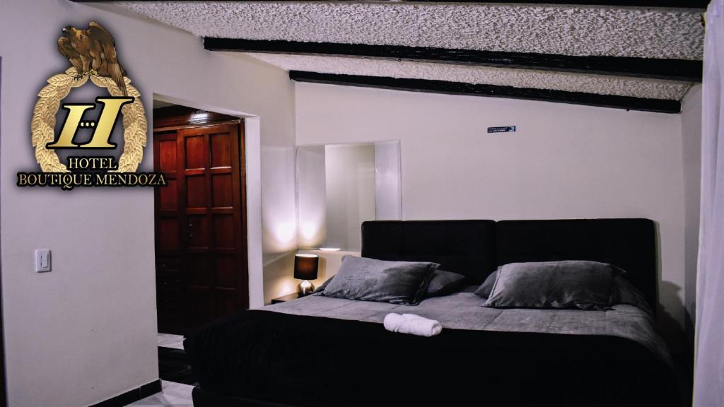 Un dormitorio con una cama negra con un cartel en la pared en Hotel Boutique Mendoza - Cerca Aeropuerto El Dorado, en Bogotá
