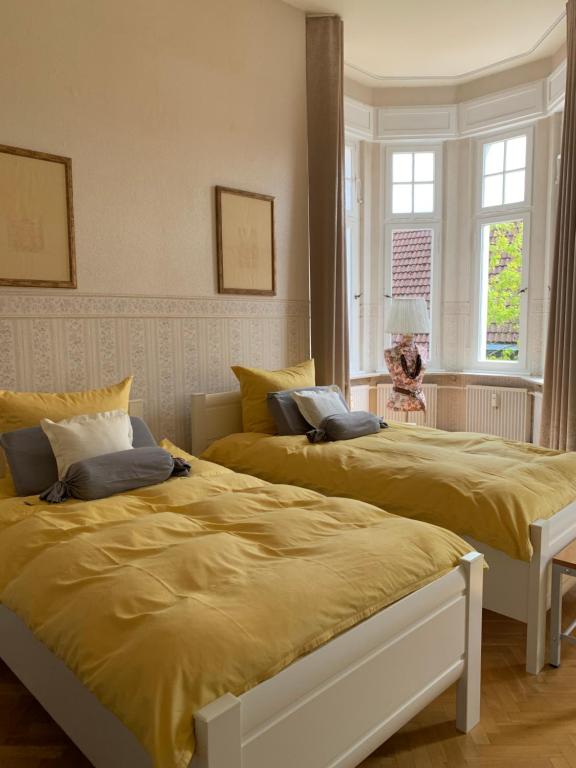 1 Schlafzimmer mit 2 Betten und gelber Bettwäsche in der Unterkunft Remedium Appartements in Vlotho