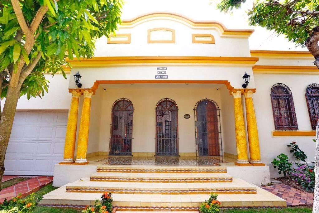 a building with yellow columns and stairs in front at Casa Blanca María Barranquilla - Authentic colonial house in Barranquilla