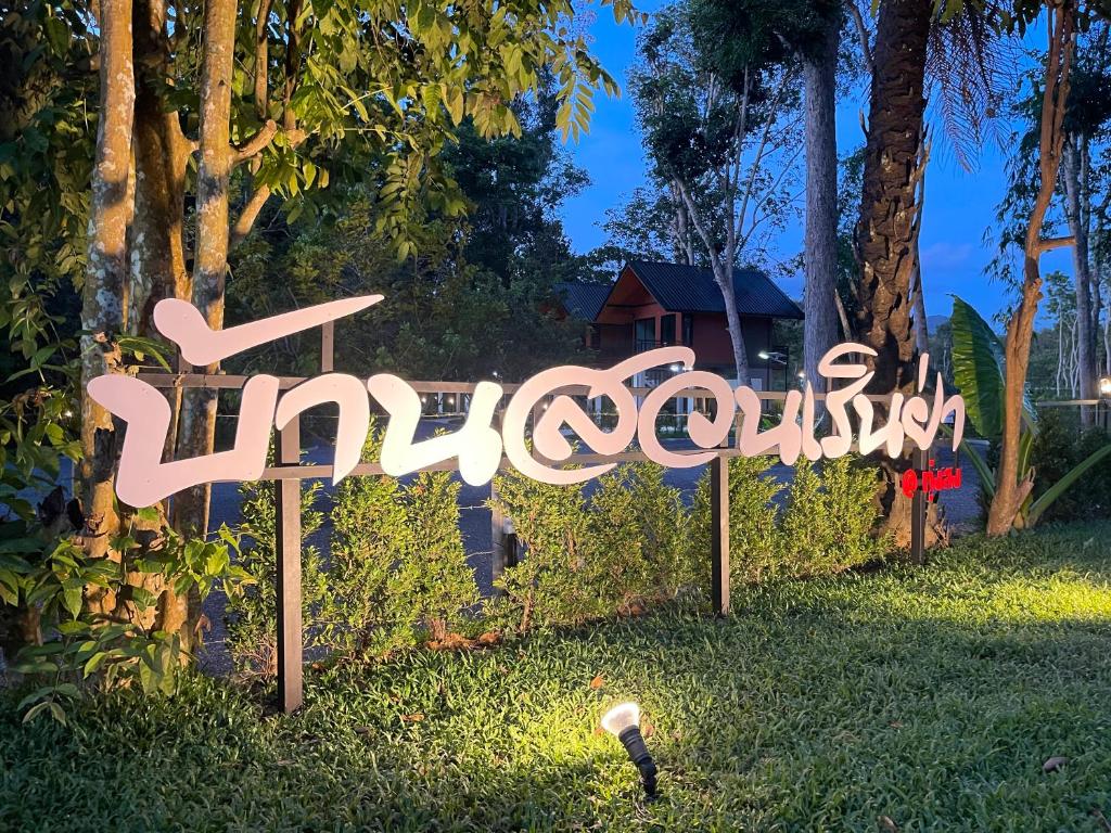 un panneau dans l'herbe devant une maison dans l'établissement บ้านสวนเรินย่า(เรินย่าคาเฟ่), à Thung Song
