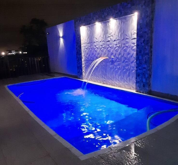 a blue swimming pool with a water fountain at casa de temporada Gabyviti in Sao Paulo