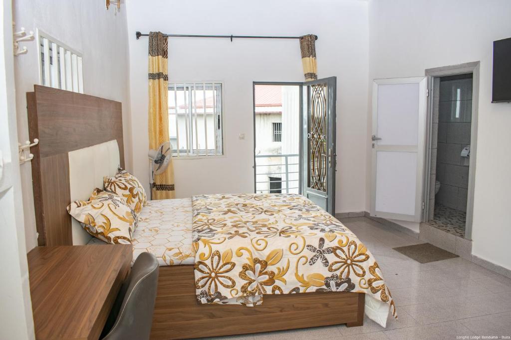 1 dormitorio con cama, mesa y ventana en Longho Lodge Bundoma - Buea, en Buea