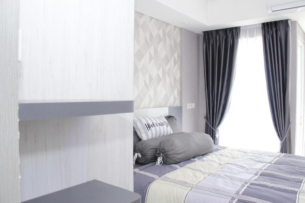 - une chambre avec un lit à côté d'une fenêtre dans l'établissement Apartemen Skylounge Makassar, à Makassar