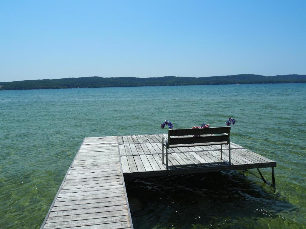 a bench sitting on a dock in the water at Cavalier Cottage - Private Lakefront W Kayaks! in Honor