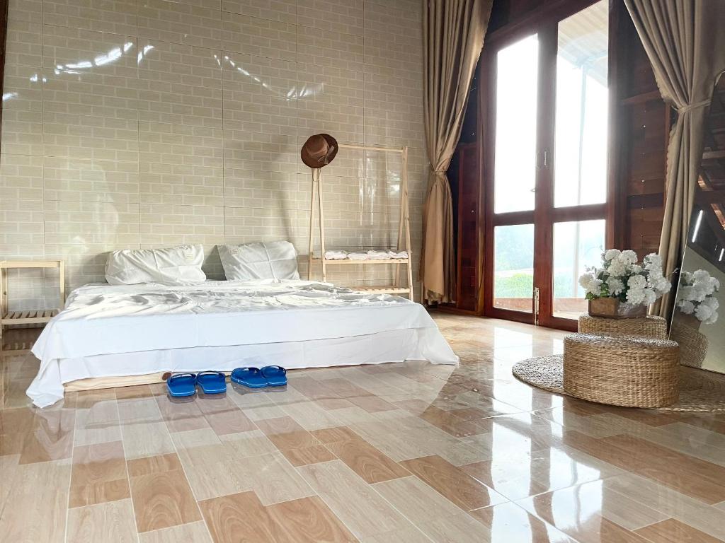 sypialnia z łóżkiem i 2 niebieskimi butami na podłodze w obiekcie Bảo Châu Garden w mieście Buôn Dru Dak Mam