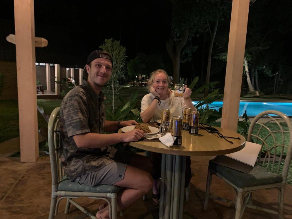 Ein Mann und eine Frau sitzen mit Getränken am Tisch in der Unterkunft The Cottage Sigiriya in Sigiriya