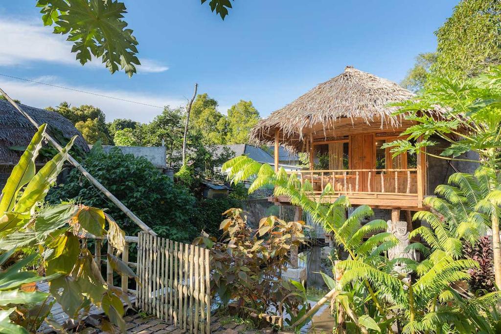 a bamboo house with a thatched roof at Onong's Homestay & Cafe in Tomohon