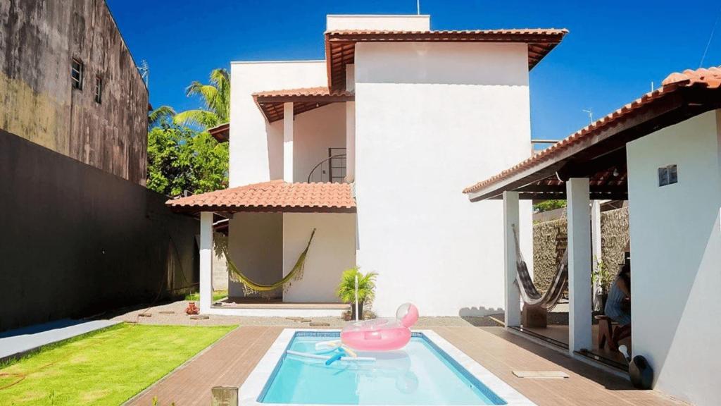 a house with a pink pig in a swimming pool at Viva Guaibim: Casa de Praia com Piscina e Churrasqueira in Guaibim
