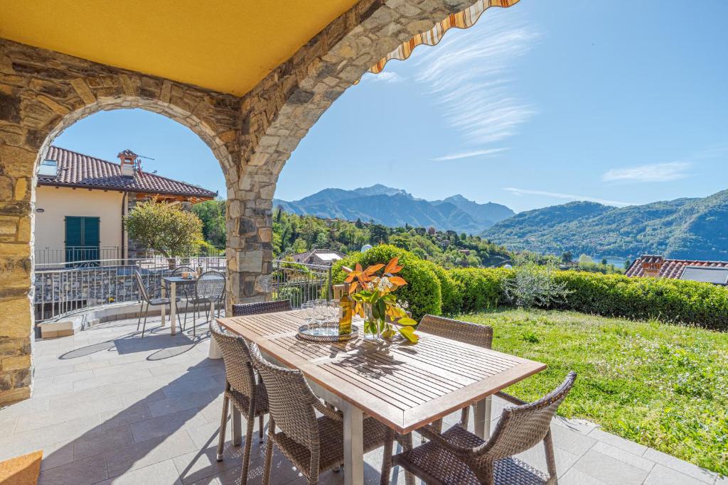 een tafel en stoelen op een patio met uitzicht op de bergen bij Villa Tremezzo in Tremezzo