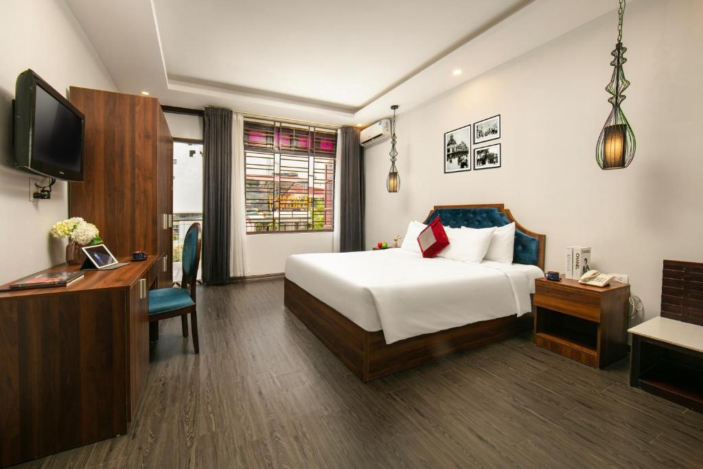 a hotel room with a bed and a desk and a tv at La Renta Premier Hotel & Spa Hanoi in Hanoi