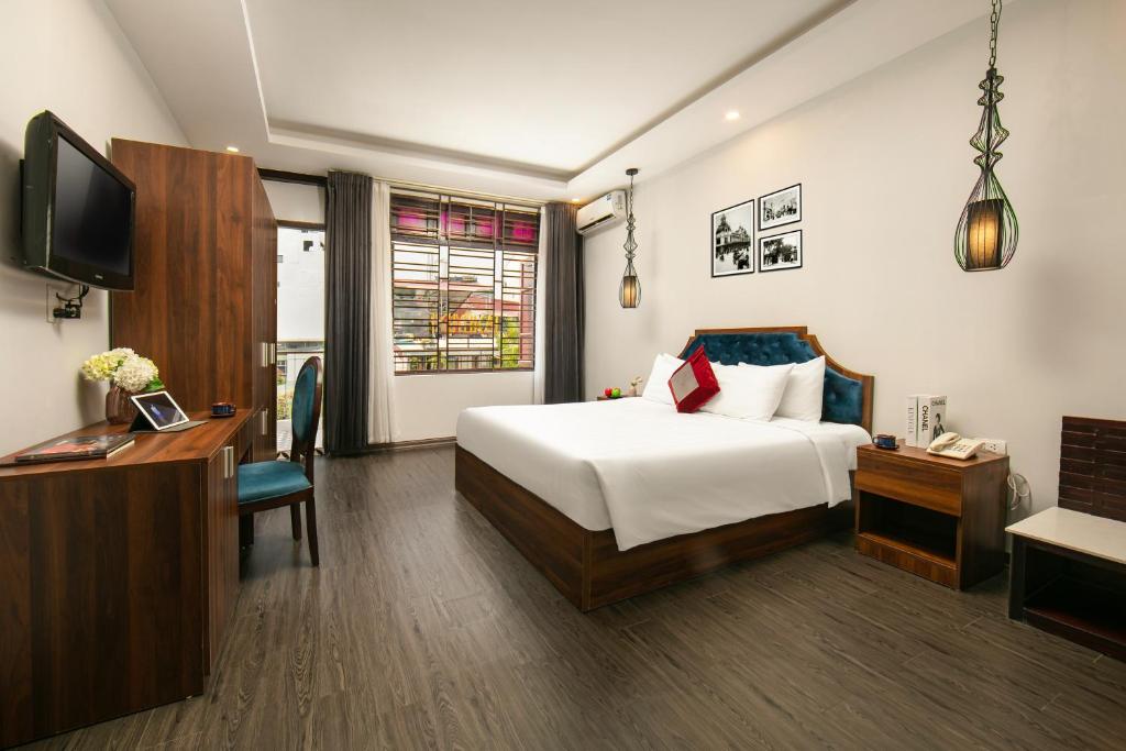 een hotelkamer met een bed, een bureau en een tv bij La Renta Premier Hotel & Spa Hanoi in Hanoi