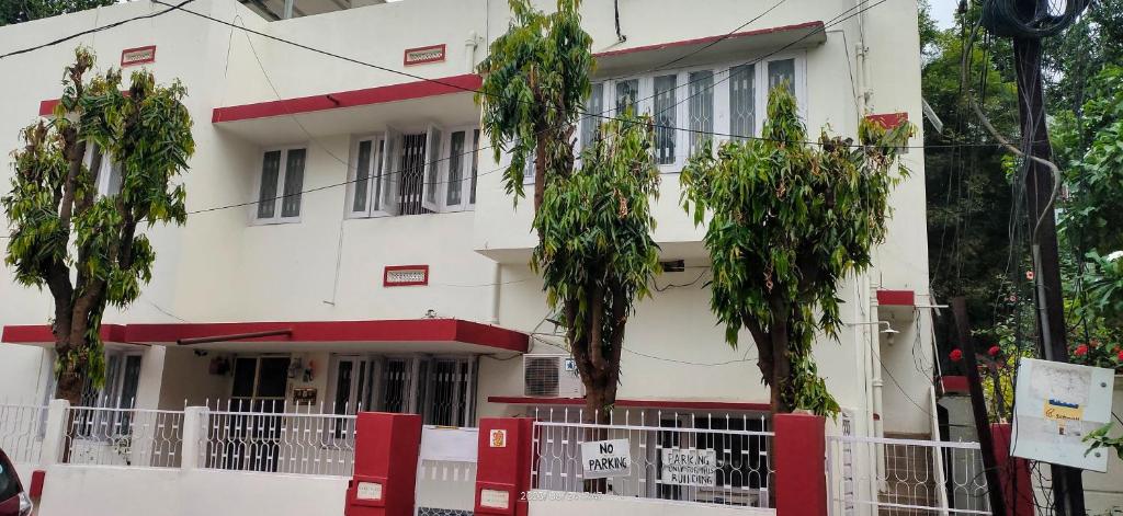 un bâtiment blanc avec des arbres devant lui dans l'établissement The Ghosh's Home stay, à Hyderabad