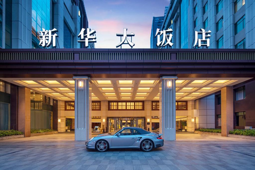 un coche aparcado frente a un edificio en voco Wuhan Xinhua, an IHG Hotel, en Wuhan