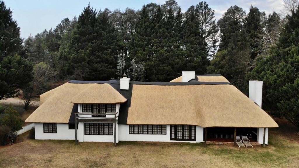 a large white house with a thatched roof at Rivermead in Himeville