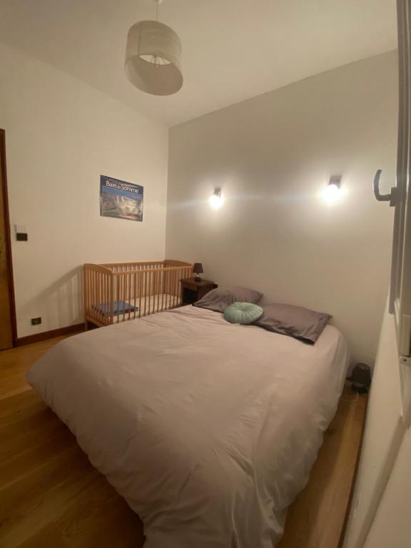 een slaapkamer met een wit bed en een wieg bij Le Saint Ju' in Friville-Escarbotin