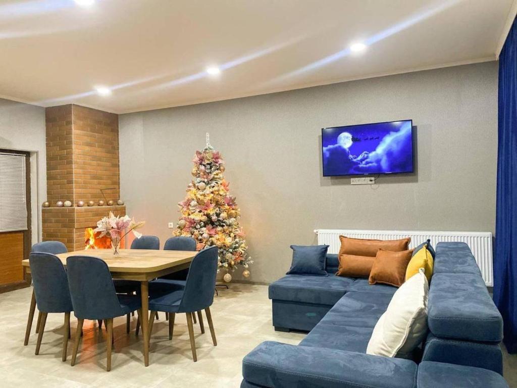 a living room with a blue couch and a christmas tree at Star Villa Bakuriani in Bakuriani
