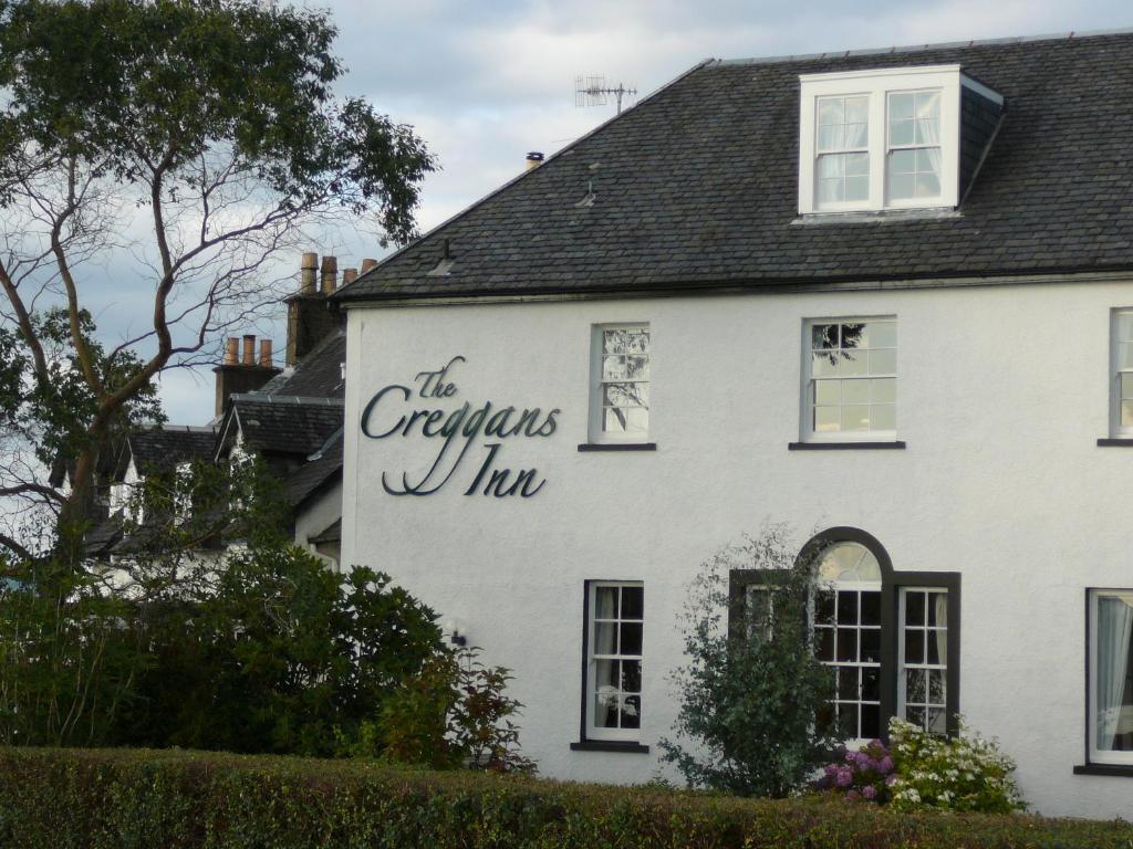 
a white building with a sign on the front of it at The Creggans Inn in Strachur
