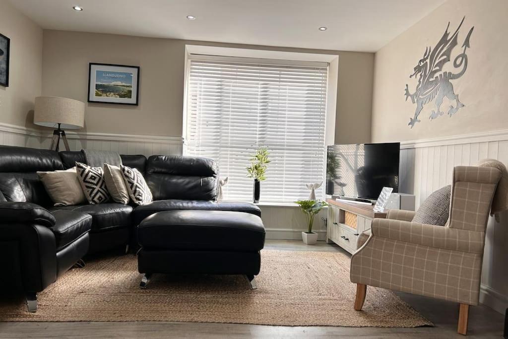 a living room with a black leather couch and a chair at 3 Bedroom Cottage in Conwy with Parking Sleeps 4 in Conwy