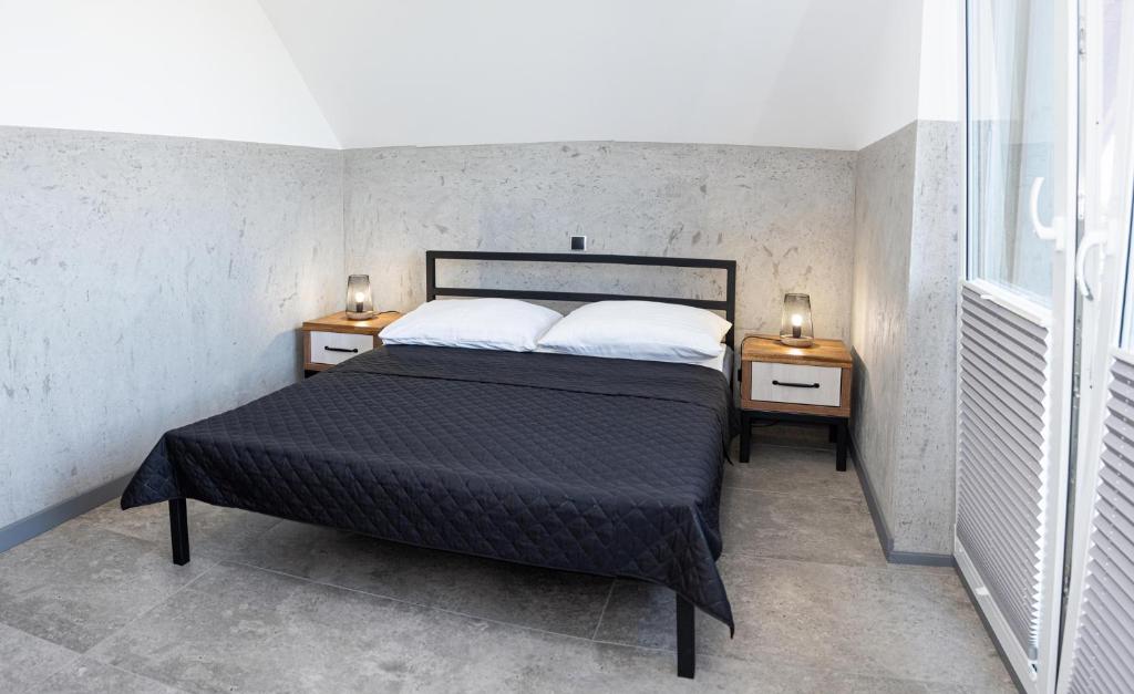 1 dormitorio con 1 cama y 2 mesitas de noche con lámparas en Domki MEGALO, en Władysławowo