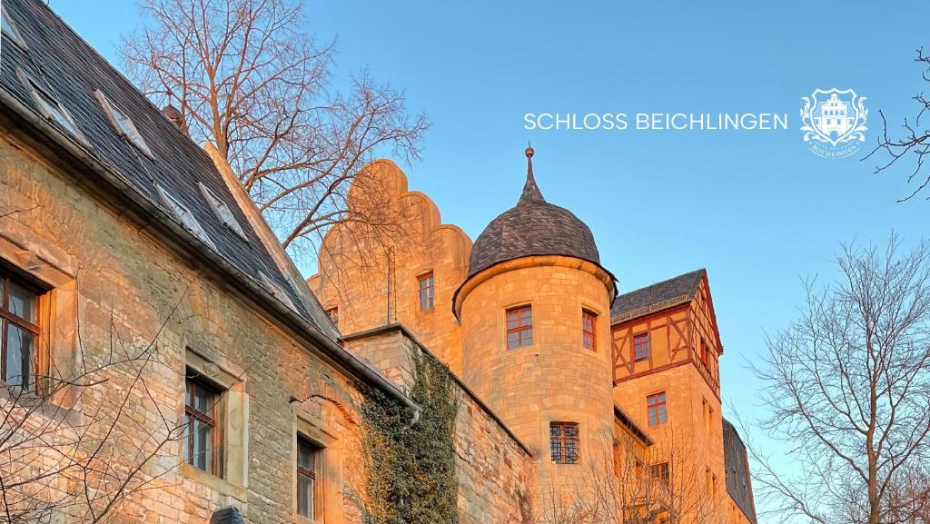 um velho edifício de tijolos com uma torre no topo em Schloss Beichlingen em Beichlingen