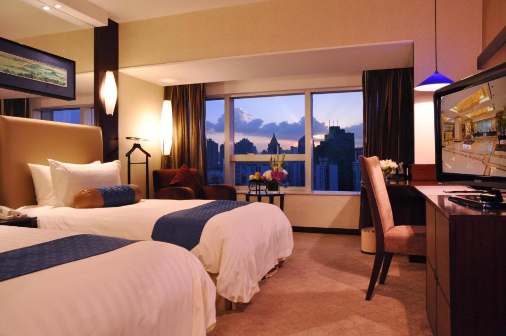 a hotel room with two beds and a flat screen tv at Jinling Purple Mountain Hotel Shanghai（Shanghai Grand Trustel Purple Mountain Hotel） in Shanghai