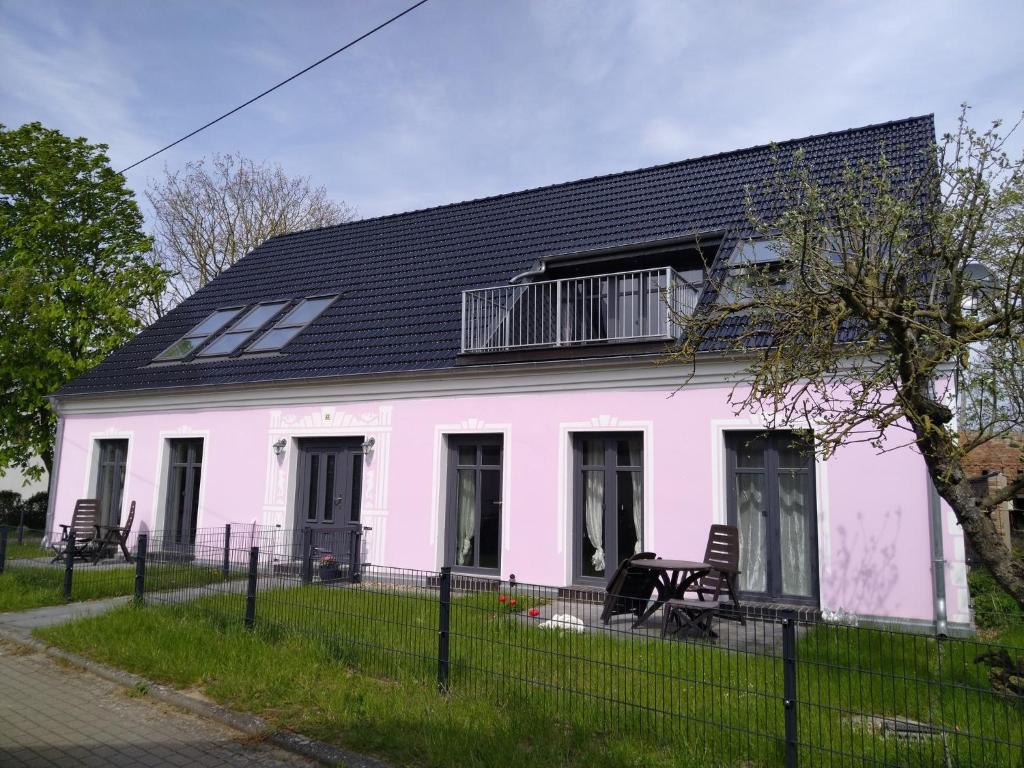 een roze huis met een zwart dak bij Wohnung Nr 4 in Bargischow