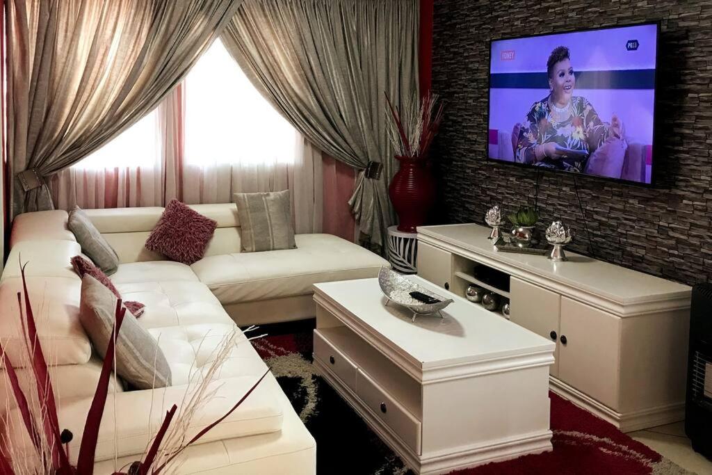 Modern style Apartment in Pretoria-Central في بريتوريا: غرفة معيشة مع أريكة وتلفزيون بشاشة مسطحة