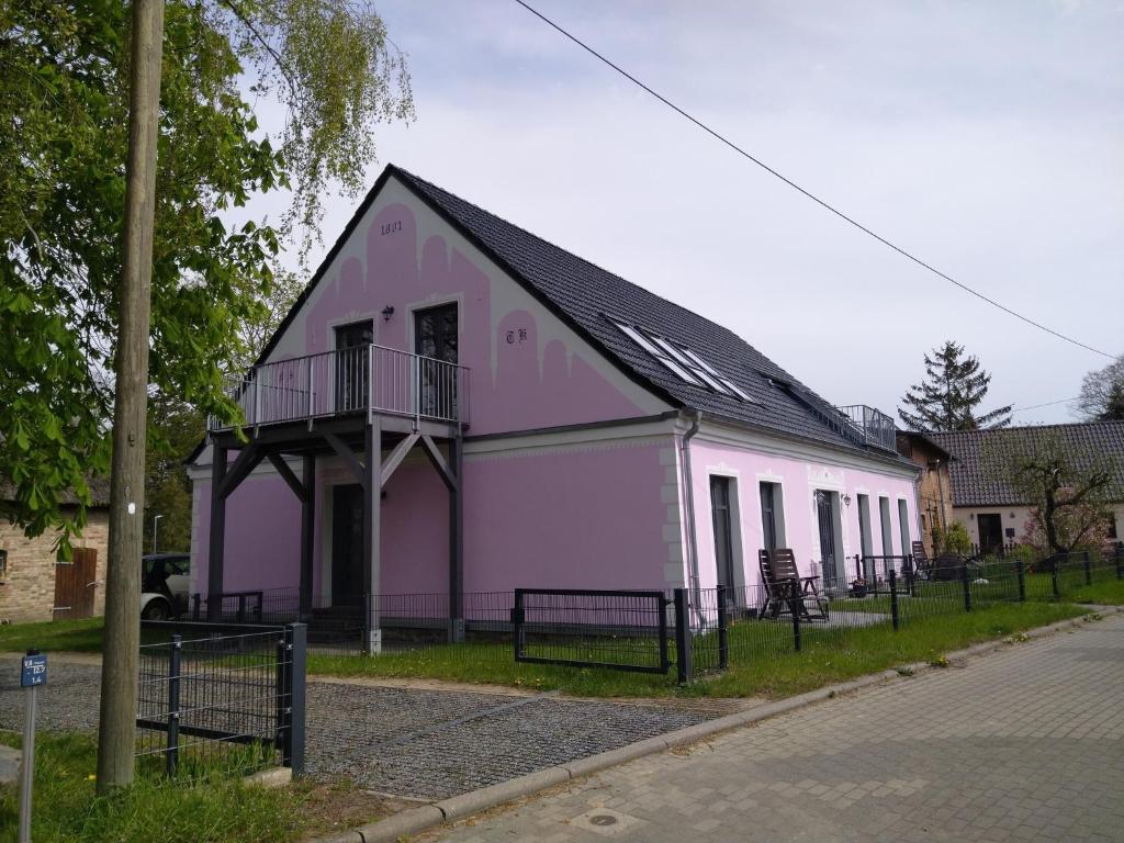 a pink and white building with a black roof at Wohnung Nr 3 in Bargischow