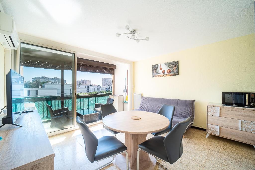 un salon avec une table, des chaises et une télévision dans l'établissement Soleil et Mer - Appt climatisé proche plage, à Saint-Cyprien