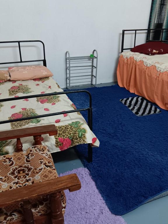 een slaapkamer met 2 bedden en een blauw tapijt bij Chambre agréable dans un endroit agréable in Port Louis