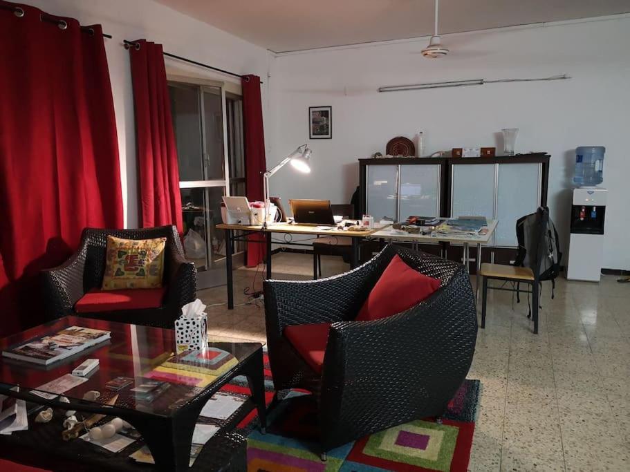 a living room with red curtains and a table and chairs at Appartement meublé au Héron in Djibouti