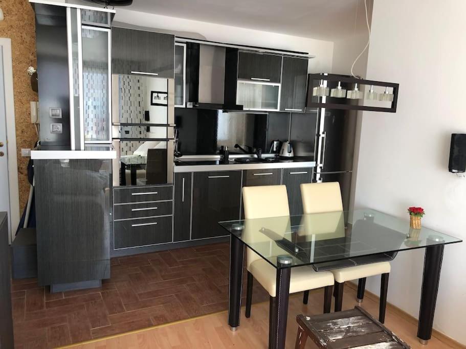 uma cozinha com armários pretos e uma mesa de vidro em Квартира у моря em Sveti Vlas