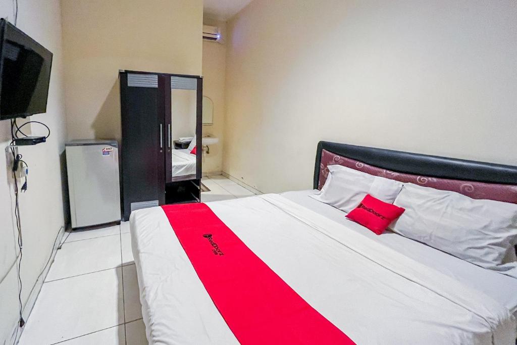a bedroom with a red and white bed and a tv at RedDoorz At Graha 99 Simomulyo in Surabaya