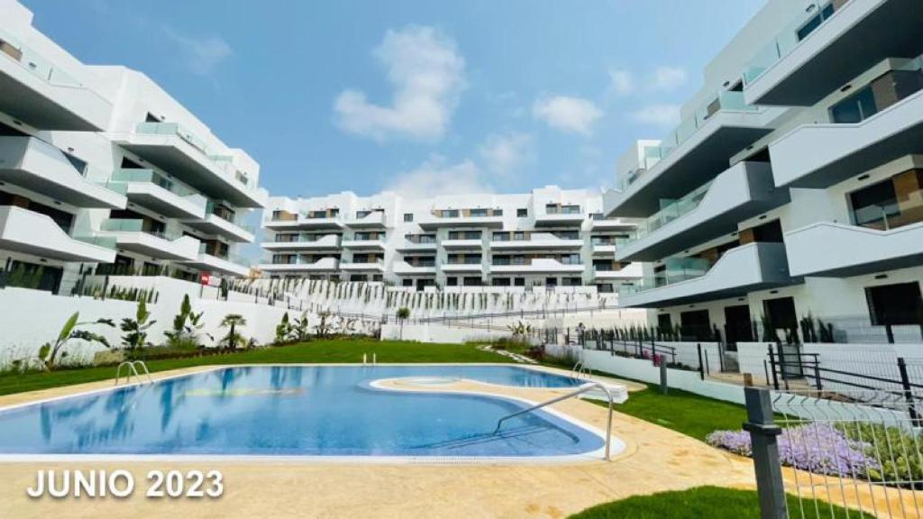a large apartment building with a swimming pool in front of it at Luxe Appartement Orihuela Costa - Villamartin -Aire Residencial - green and pool view in Orihuela Costa