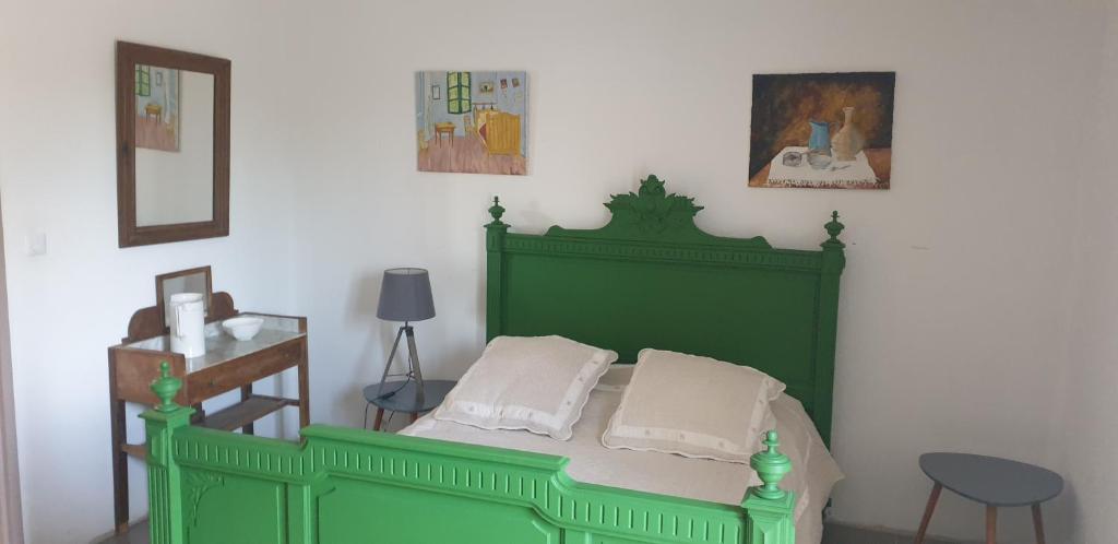 a green bed with two pillows in a bedroom at la boufanelle in Montséret