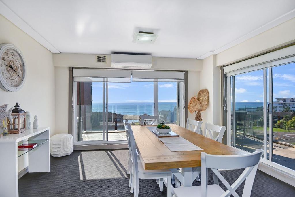 a dining room with a table and chairs and a large window at Sandy Cove Apartment The Entrance 24 in The Entrance