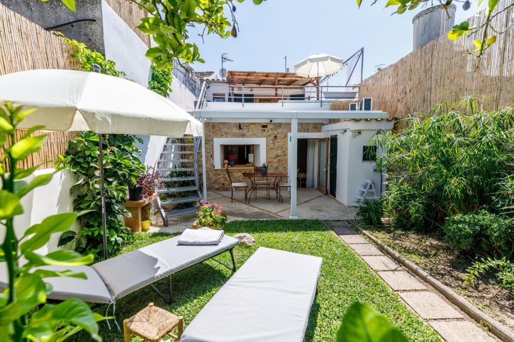 um jardim com guarda-sol e cadeiras e uma casa em Can Mateu em Campanet